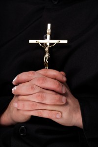 26488597 - priest is holding a cross which is a christian symbol