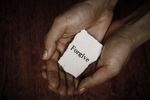 37174257 - forgive stone block in hands with dark background.