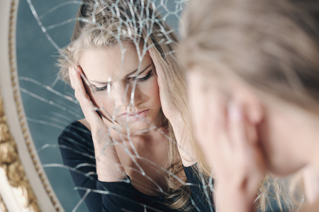 66120325 - girl with depression reflected in broken mirror